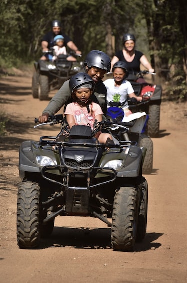 A group of people riding ATVs on a dirt path surrounded by trees. 5