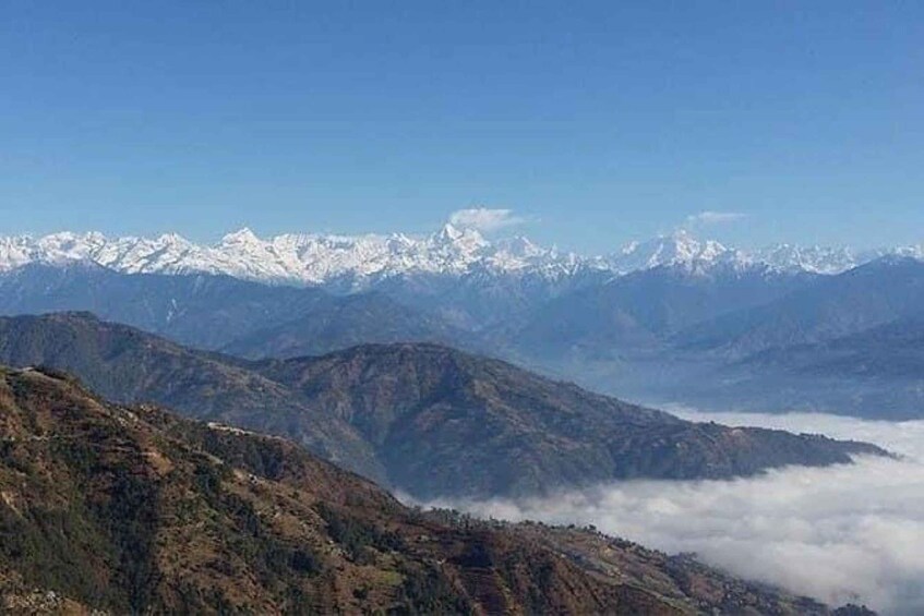 A mountain range with snow-capped peaks and a valley with clouds below. 1