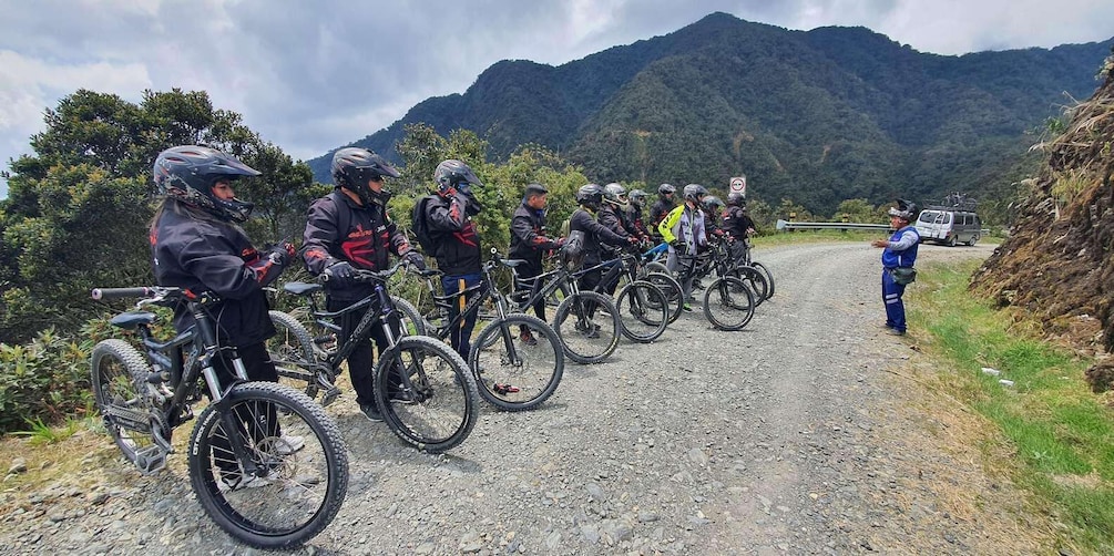 A group of mountain bikers on a gravel road with a van and a no parking sign in the background. 4