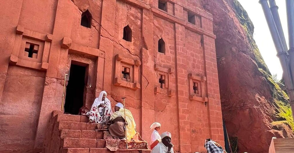 A red sandstone building with arched windows and a doorway. 2