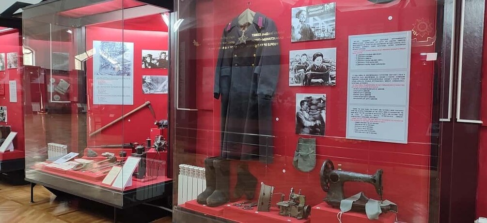 En udstilling på et museum med røde vægge, historiske fotografier og ældre maskiner. 5