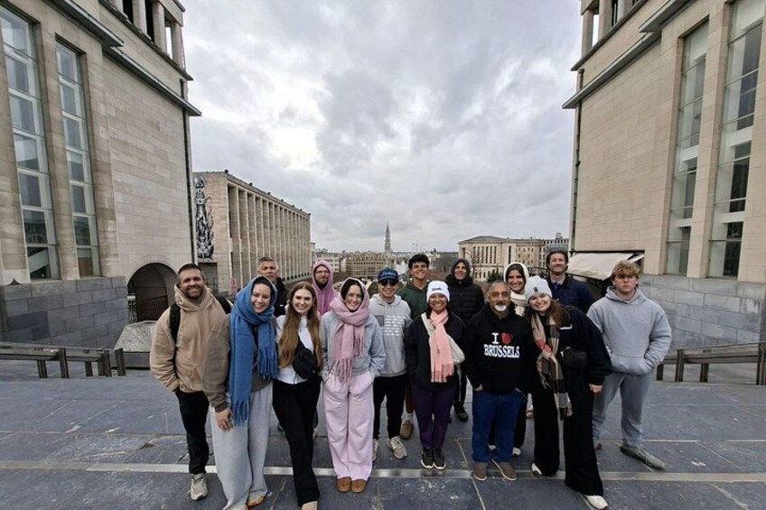A group of people standing in front of a building with large windows and a statue. 5