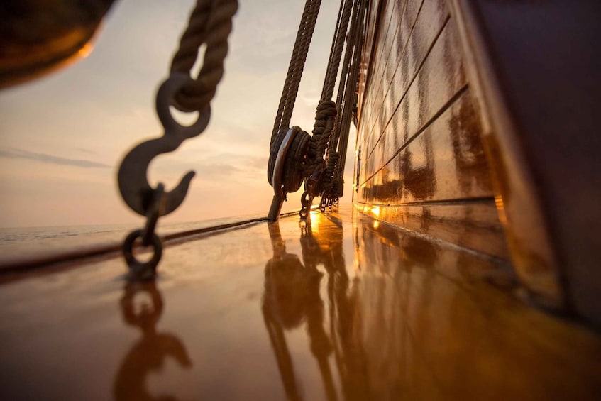 A ship's deck with ropes and a pulley system, reflecting the sunset. 4