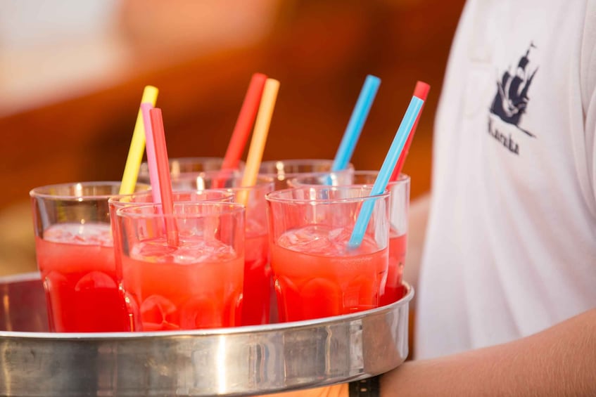 A tray with several glasses of red beverage, each with a colorful straw. 3