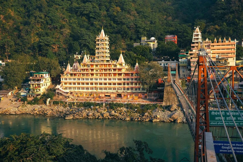 A riverside temple complex with a large, multi-tiered pagoda and a suspension bridge. 4