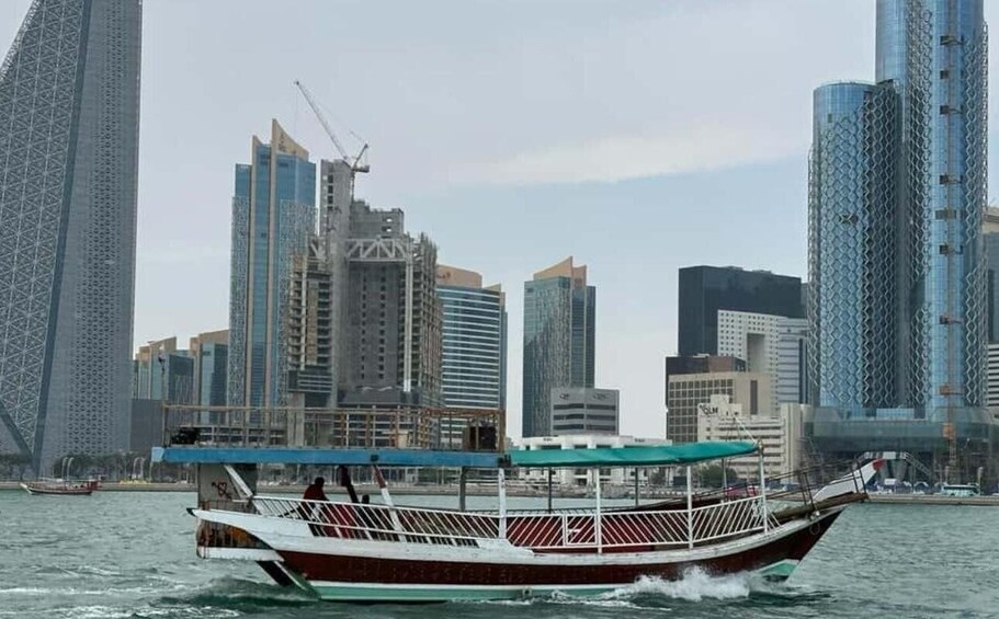 A traditional wooden boat on water with a city skyline in the background. 4