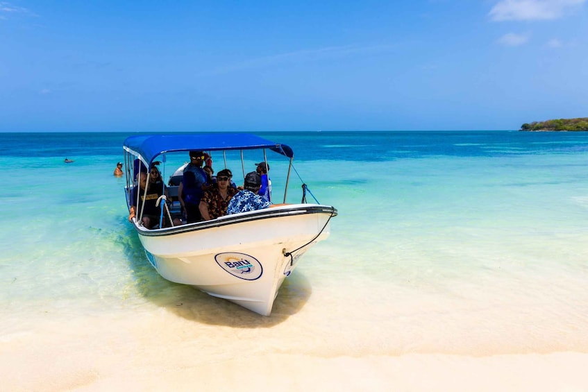 Un bote con gente en una playa turquesa y transparente. 4