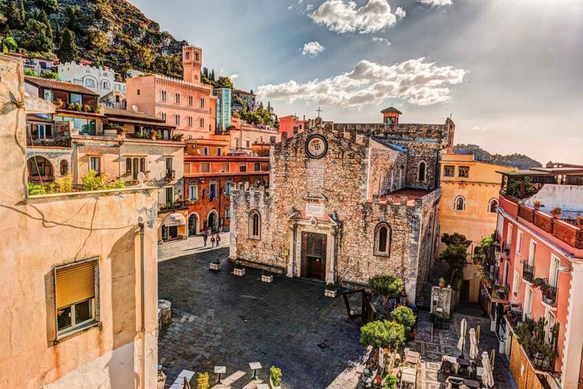 A historic town square with a prominent church, cobblestone streets, and colorful buildings. 2