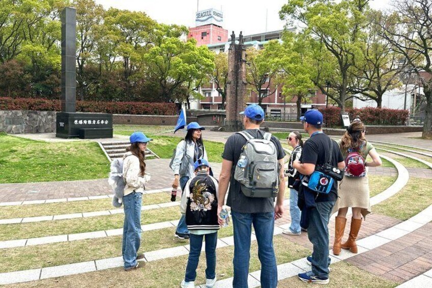 A group of people walking on a paved path in a park with grass and trees. 2