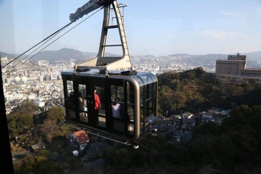 A cable car suspended over a city with a mountainous backdrop. 3