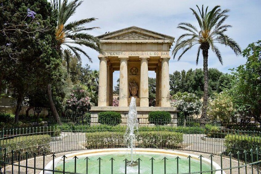 Un edificio de estilo clásico con columnas, rodeado por una fuente y palmeras. 4