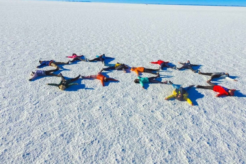 A group of people lying on the snow in a circular formation. 5
