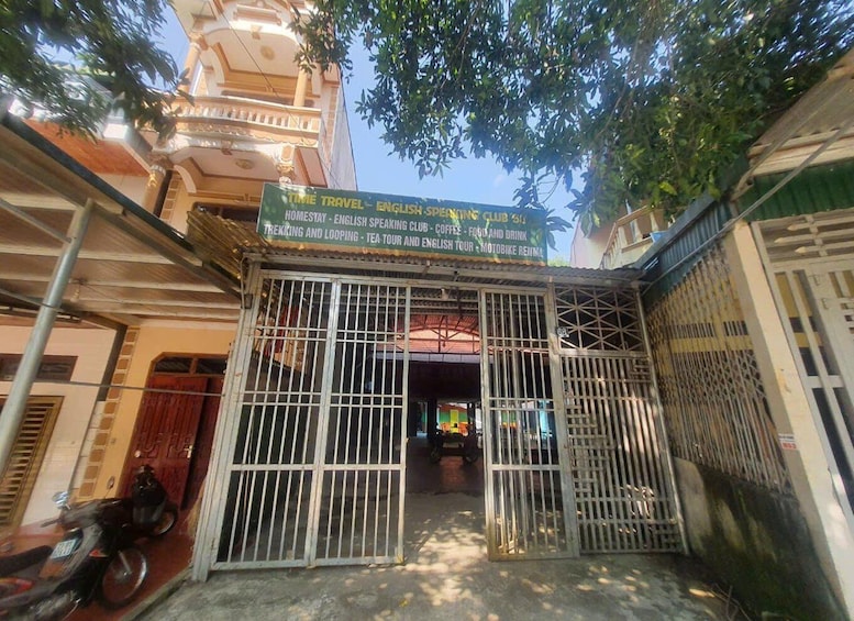 A gated entrance to a building with a signboard advertising services like trekking, tea tour, and English speaking club. 4