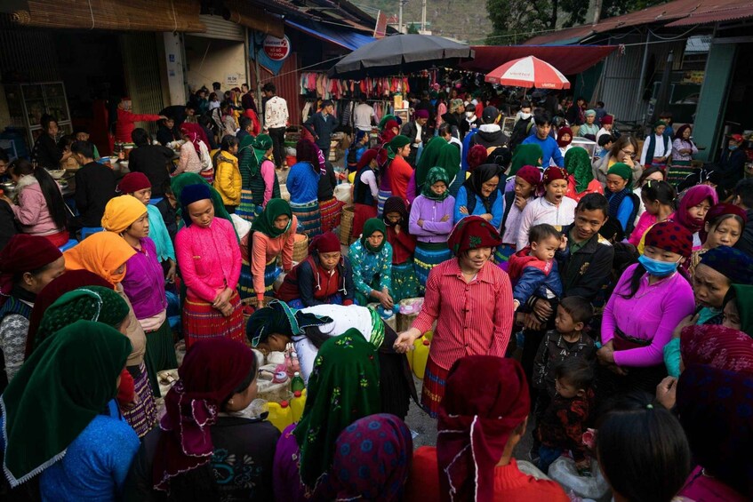 A crowded outdoor market with people shopping and socializing. 3