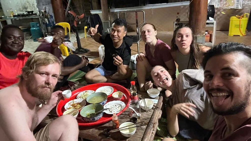 A group of people sitting around a table with various dishes and drinks. 2