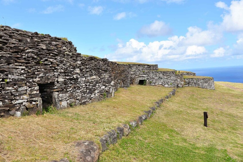 A stone wall with a grassy field and a clear sky. 5