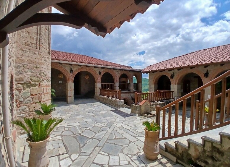 A courtyard with stone flooring, red-tiled roofs, and arched doorways. 5