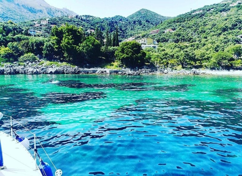 A boat on clear turquoise water with a mountainous landscape in the background. 3