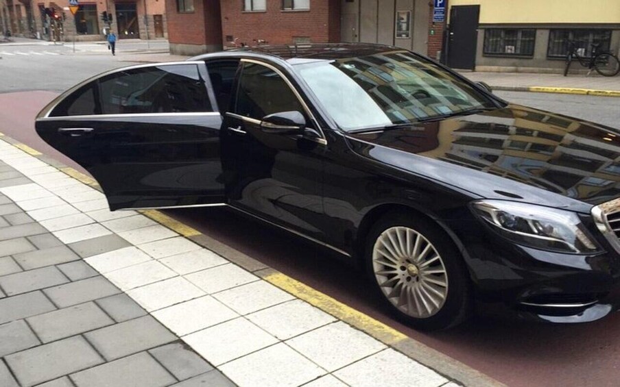 A black car parked on a city street with its door open. 5