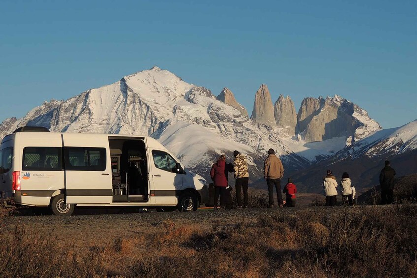 A white van parked on a grassy field with a mountainous backdrop. 3