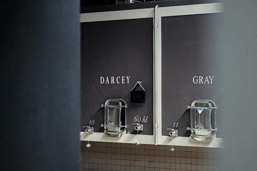 Ett toalettutrymme med två handfat, varav det ena är märkt med namnet ”DARCEY” och det andra med ”GRAY”, samt med vattenautomater. 5