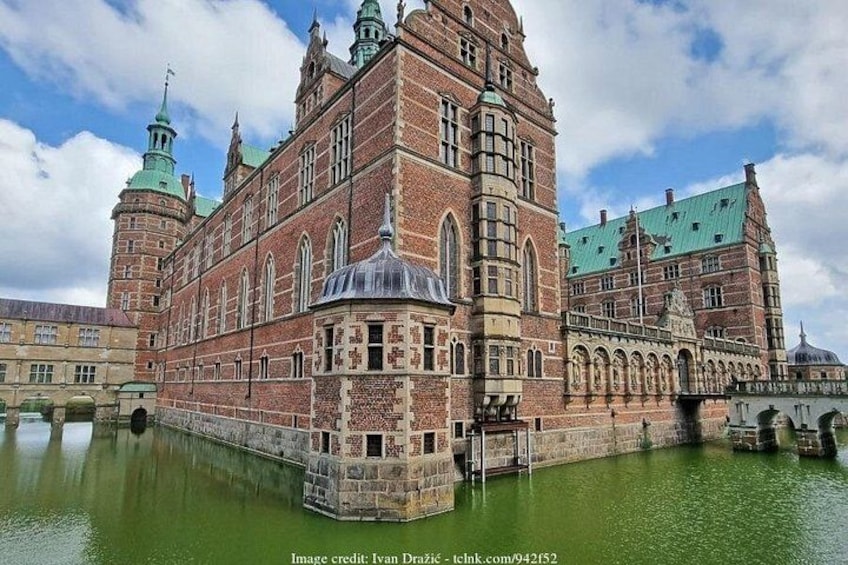 Een historisch gebouw met een grote centrale toren, een koepelstructuur en een gracht eromheen. 3