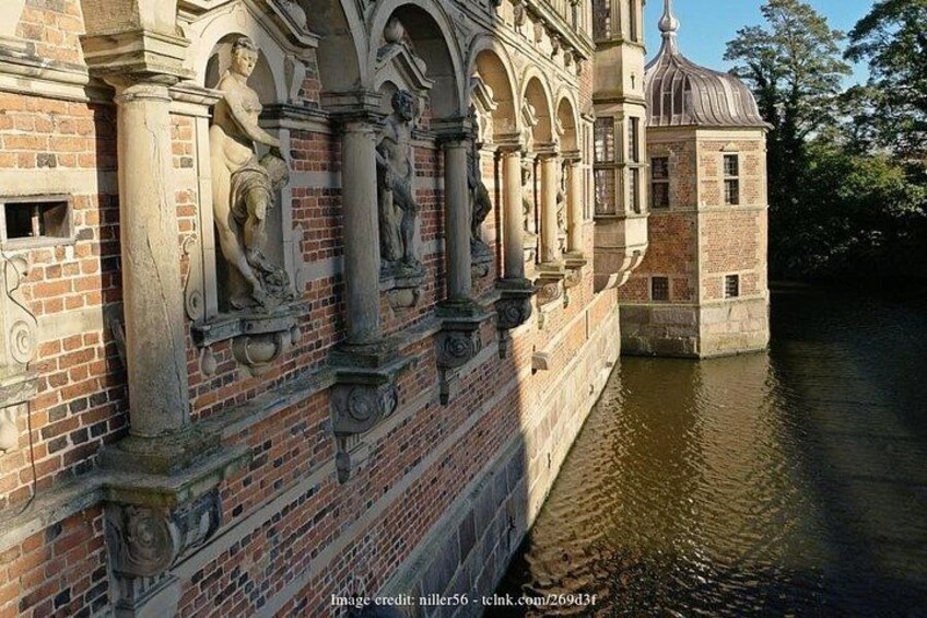 Een historisch gebouw met ingewikkelde stenen decoraties en een watergracht. 2