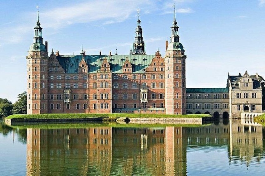 Een groot historisch gebouw met meerdere torens, weerspiegeld in het water. 1