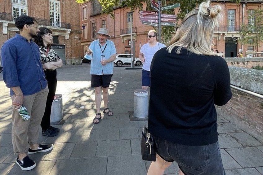 A group of people standing on a sidewalk, engaged in a discussion. 3