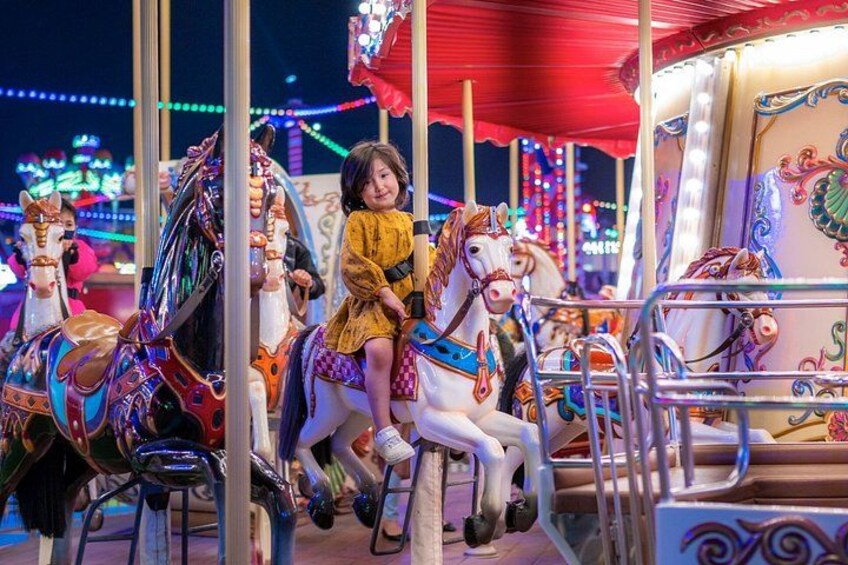 A carousel with colorful horses and a child riding one. 5