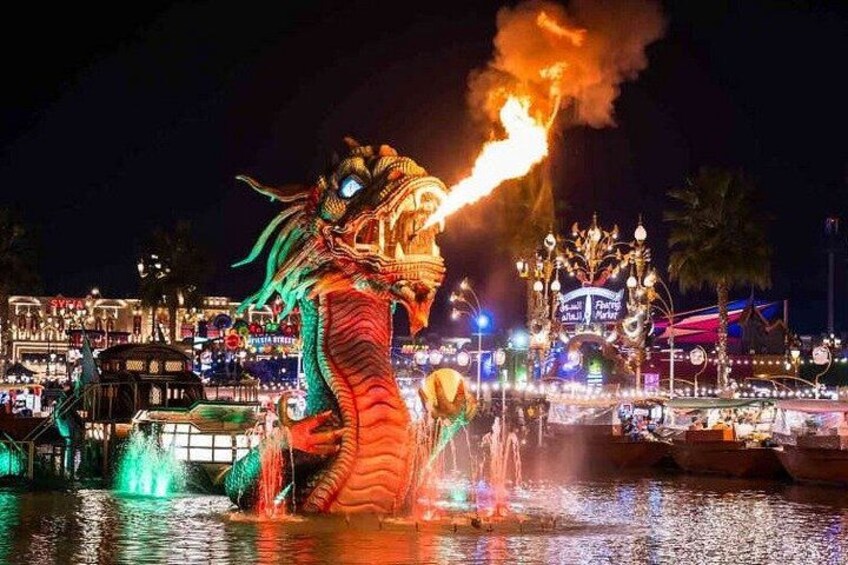 A dragon with fire breathing, water fountains, and illuminated buildings at night. 3