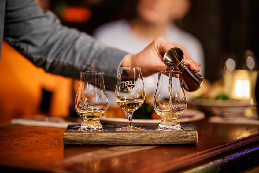 A person pouring a drink into a glass labeled 'TEELI' at a bar. 2