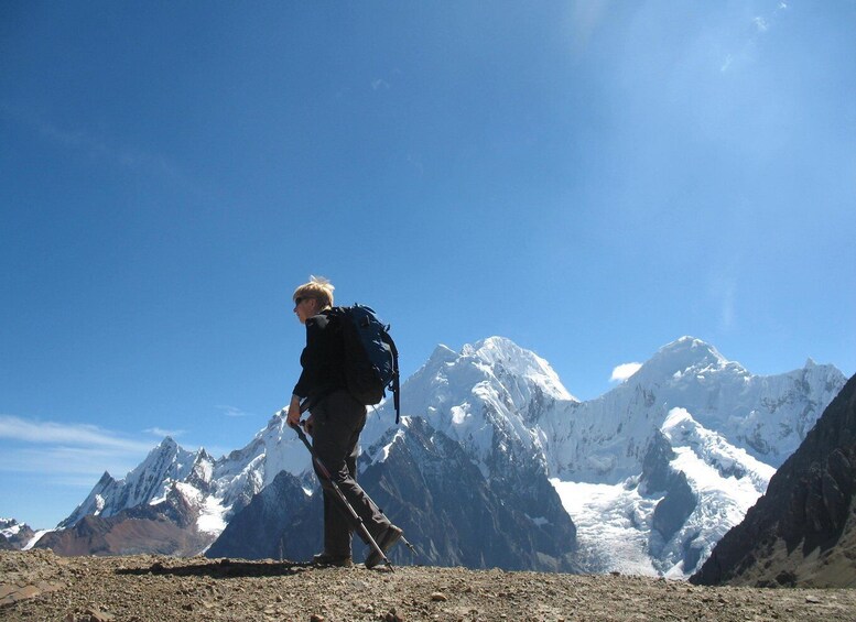 A hiker with a backpack on a rocky mountain terrain with snow-capped peaks in the background. 5