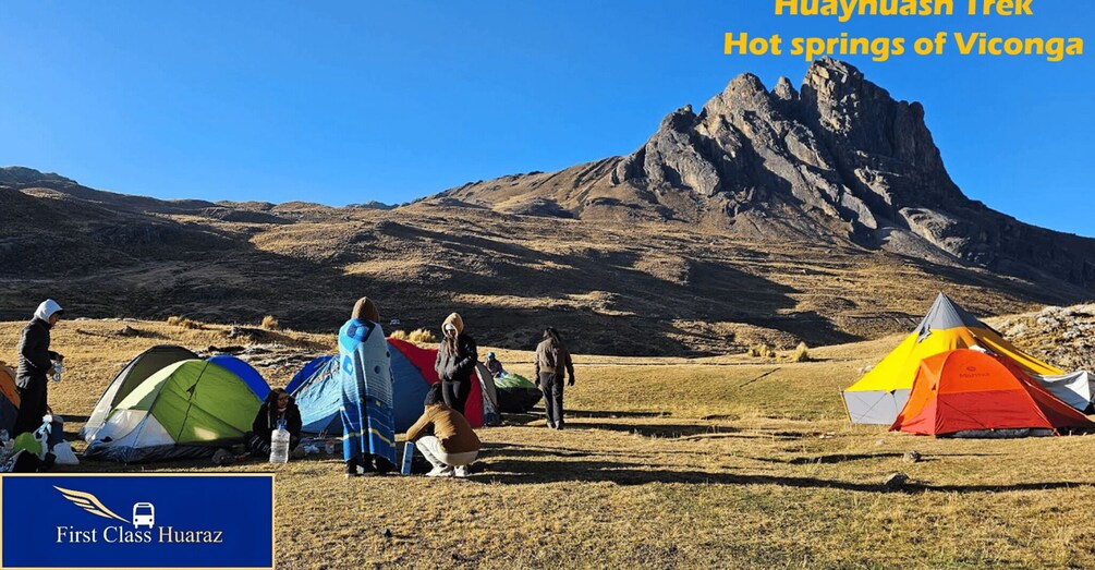 A group of tents in a dry grass field with a mountain in the background. 5