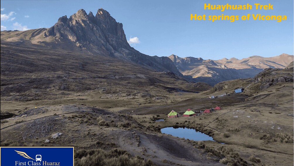 A mountainous landscape with a prominent peak, a small body of water, and several tents. 5