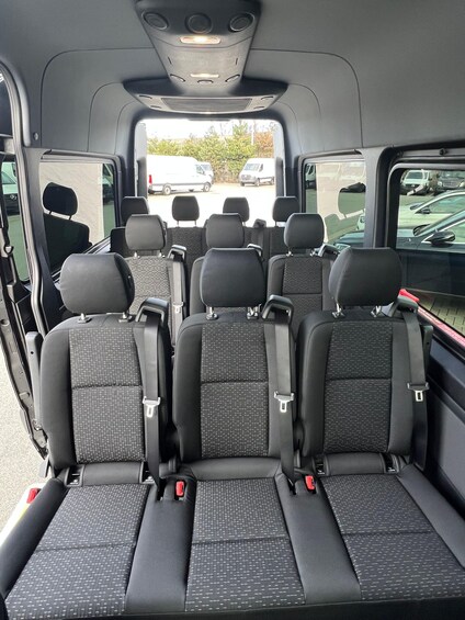 The interior of a vehicle with multiple rows of seats, each equipped with seat belts and headrests. 5