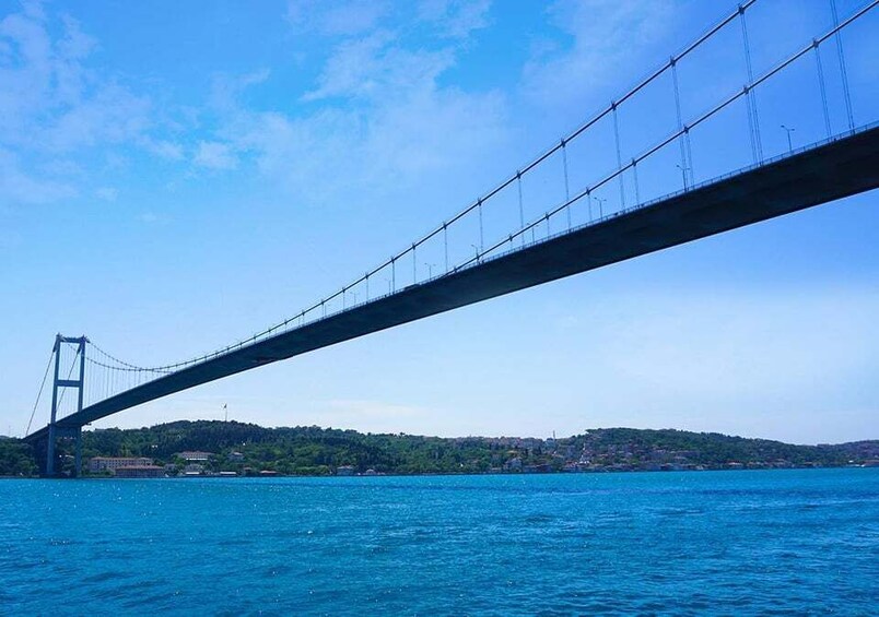 Un grand pont suspendu enjambant une étendue d’eau, avec un paysage vallonné en arrière-plan. 4