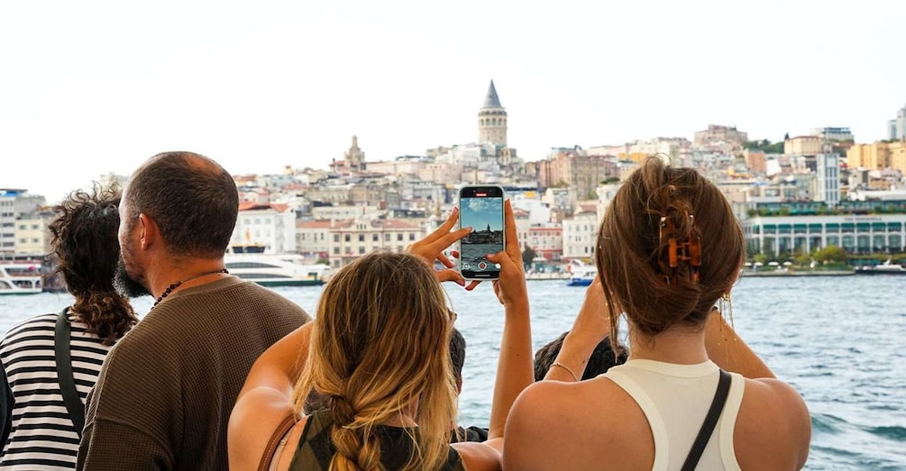 Un groupe de personnes prend une photo d’un paysage urbain, avec une tour imposante en arrière-plan. 1