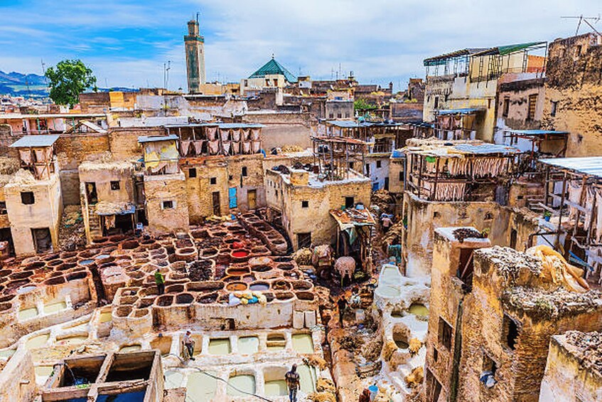 A traditional market with terracotta flooring, historic buildings, and a mosque in the background. 2