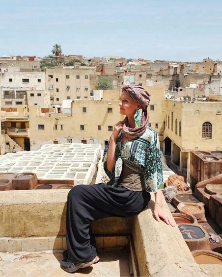 A person sitting on a rooftop overlooking a densely packed urban area with traditional buildings. 5