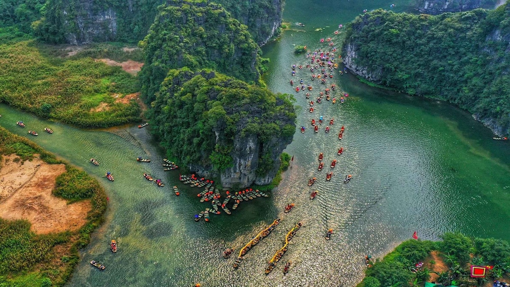 A river with numerous boats, surrounded by lush green cliffs. 1