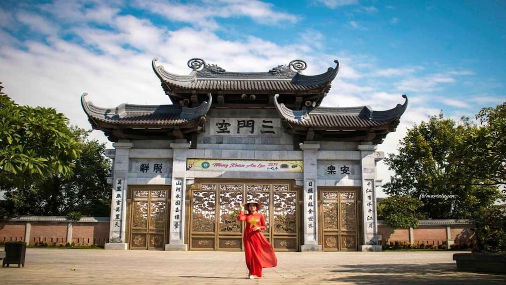 A traditional Chinese gate with intricate designs and a woman in a red dress standing in front. 4