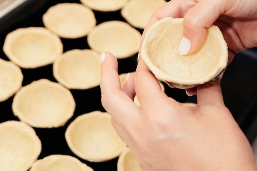 Des mains tenant une pâte à tarte, avec plusieurs autres pâtes à tarte visibles en arrière-plan. 2