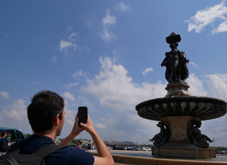 A person taking a photo of a fountain with a statue of a woman and two lions. 2