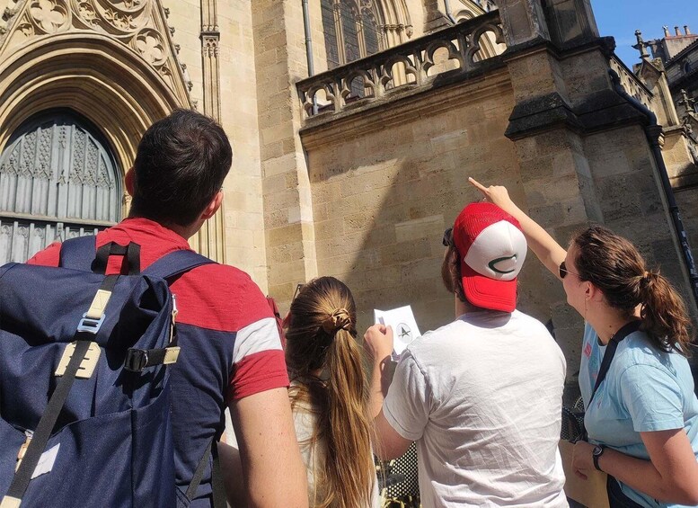 A group of people standing in front of a historic building with intricate stonework and a large arched doorway. 5
