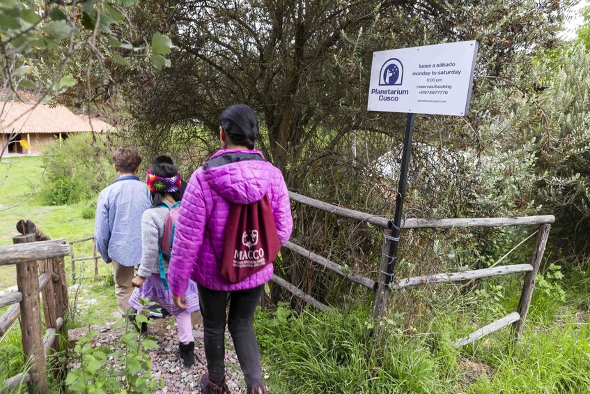 Un grupo de personas caminando por un sendero de madera hacia un cartel. 2