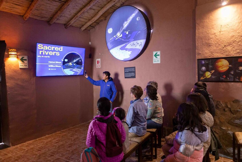 Presentación sobre 'Ríos Sagrados', con una pantalla grande mostrando un mapa y una persona señalándolo. 1