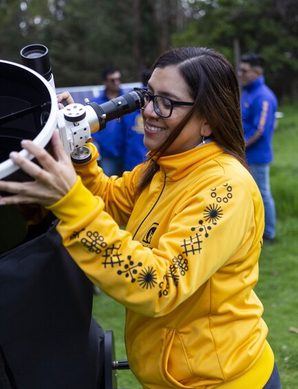 Una persona con una sudadera amarilla usando un telescopio. 5