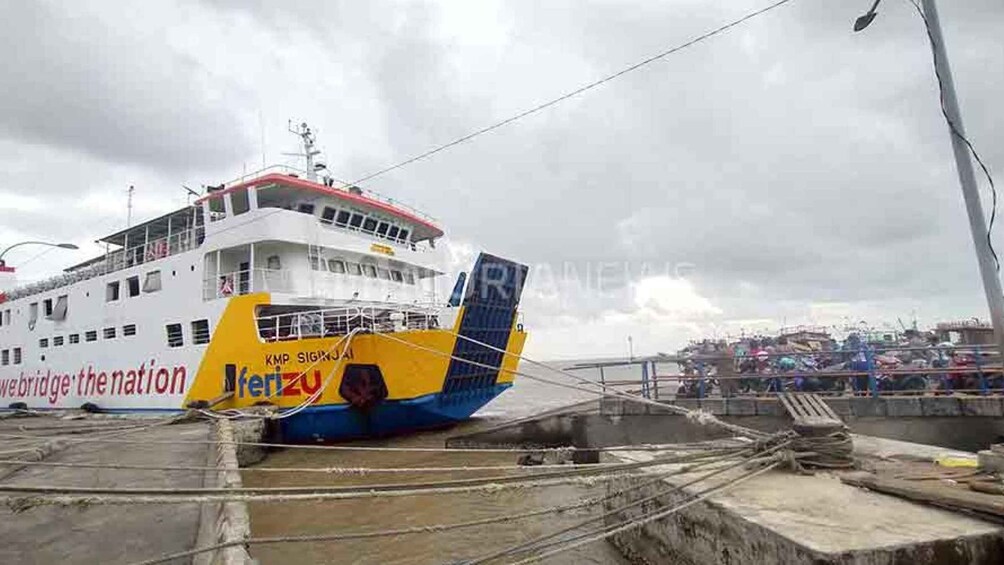 A ferry docked at a pier with a crowd in the background. 4
