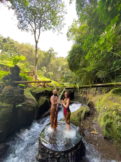 Two people standing in a natural water feature surrounded by lush greenery. 1